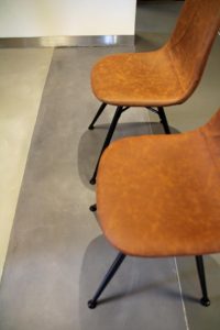 Gietvloer nature met 2 stoelen bovenzijde met zwarte stalen poten en cognac leren zitting