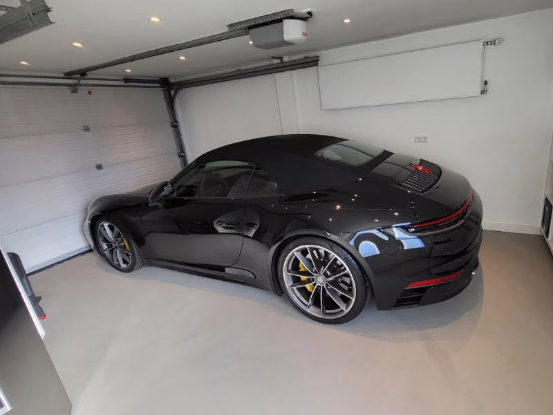 Sterke lichtgrijze gietvloer in een garage met een zwarte sportauto