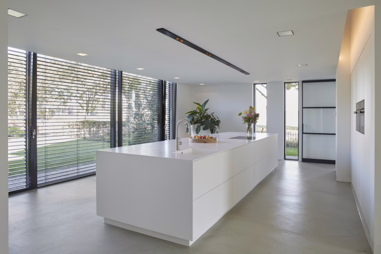 Design Woonbeton in Breda in de keuken met wit kookeiland en zachte off-white microcement vloer