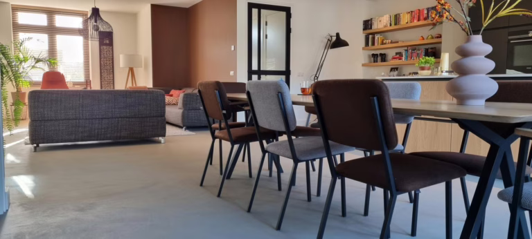 Warme lavasteen gietvloer Valkenswaard in kleur Sira — totaalbeeld van woonkamer en open keuken in een boerderij-stijl nieuwbouw.
