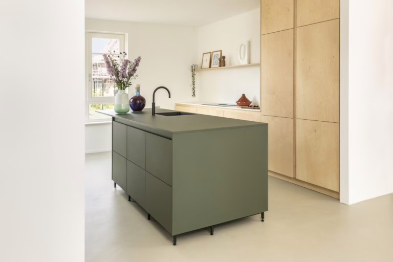 Pure Base woonbeton Eindhoven — totaalbeeld van een Scandinavische keuken met licht berken-maatwerk en groen keukeneiland op 100 m² Kiezelgrijs.