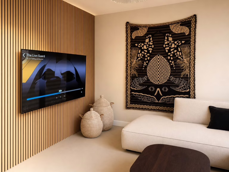 Bio Cement gietvloer Herten — gezellige woonkamer met houten latwand, tv en decoratief wandkleed.