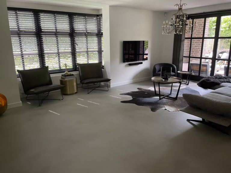 Zithoek met design woonbeton Sint-Michielsgestel in Stone Grey, met kroonluchter en tuinuitzicht