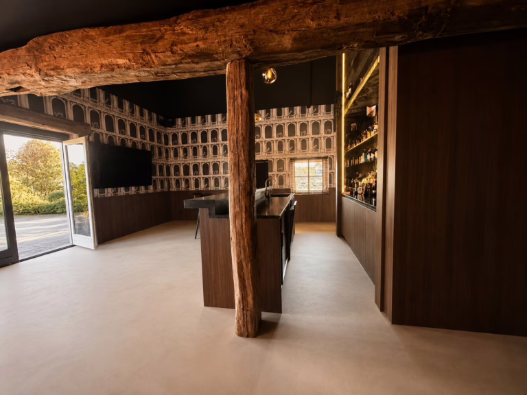 Minimal Sand gietvloer Best — overzicht van de thuisbar met groen marmer en rode fluwelen bank.