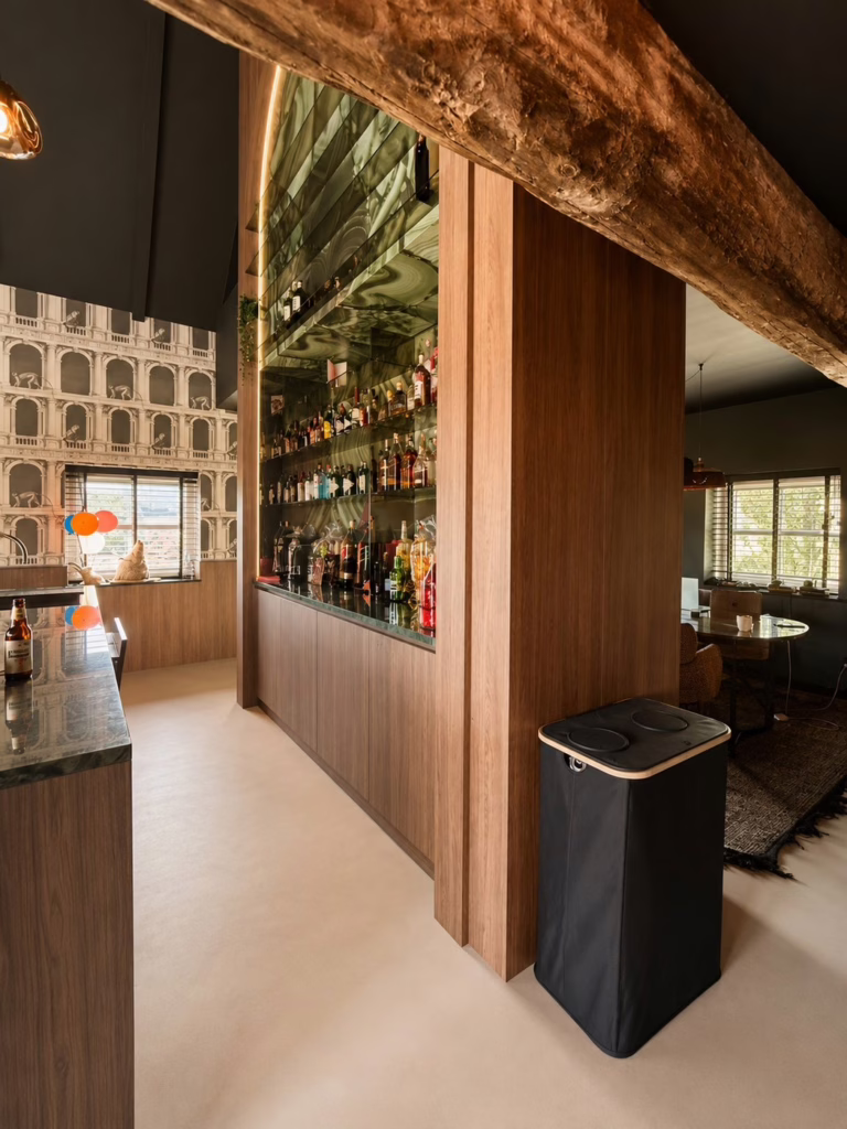 Detail Minimal Sand gietvloer Best — bar met groen marmer, roze krukken en colonna-behang.