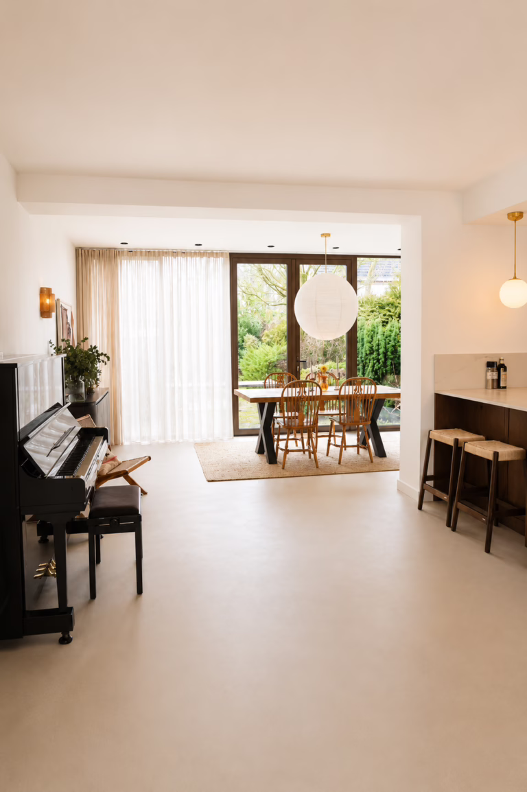 Open woonkamer met piano, eettafel en bar op Minimal Sand kwartsiet gietvloer in Berkeley — Sint-Michielsgestel