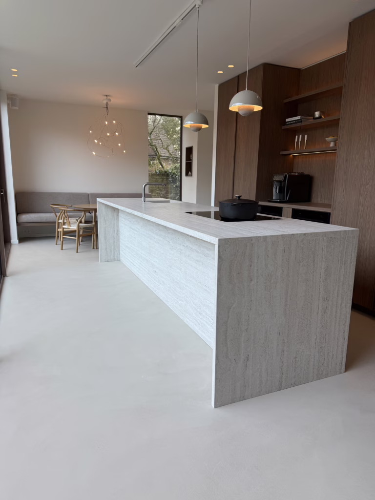 Moderne Japandi keuken met Minimal Sand kwartsiet gietvloer, travertijnen kookeiland en maatwerk kastenwand — Wijchen