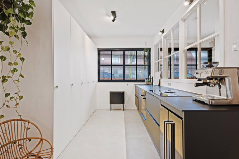 Venetiaans Woonbeton Helmond in de open keuken — off-white microcement vloer met zwart keukenblok en matte PU-afwerking