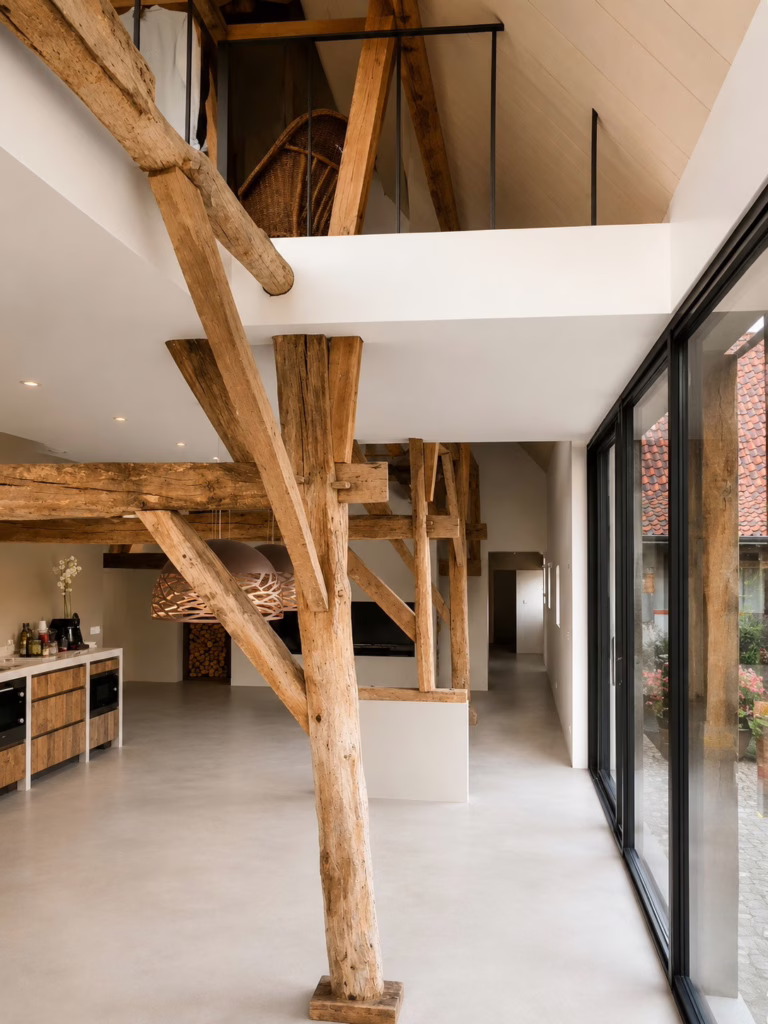 Industriele betonnenvloer in kleur Sand Stone in een bijgebouw te Best, met karakteristieke houten A-frame spanten en vide
