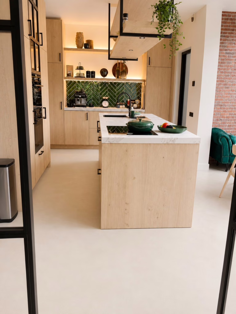 Kookeiland met marmerlook aanrecht op Minimal Sand gietvloer kleur Madison en groene visgraad-tegelwand