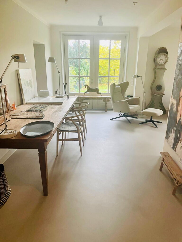 Eetkamer met lange houten tafel en tuindeuren, met daglicht over de lavasteen gietvloer