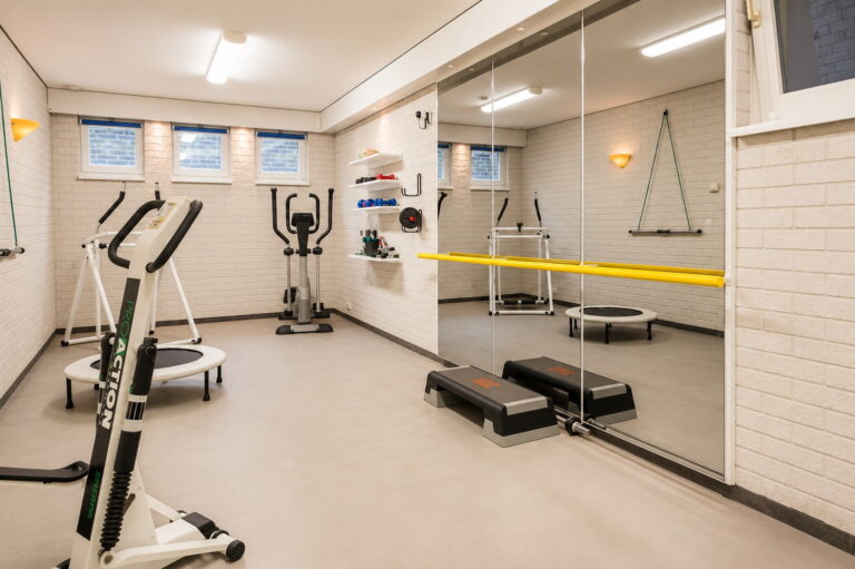 Lichtgrijze PU gietvloer in kleur NCS 2005-Y20 in de fitnessruimte van een moderne villa te Schaijk, met spiegelwand en balletbarre
