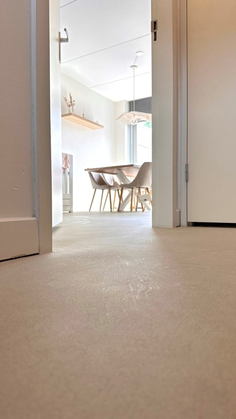 Detailopname op vloerniveau van de structuur van de Solido kwartsiet gietvloer in Best, met doorkijk door de deuropening naar de eethoek.