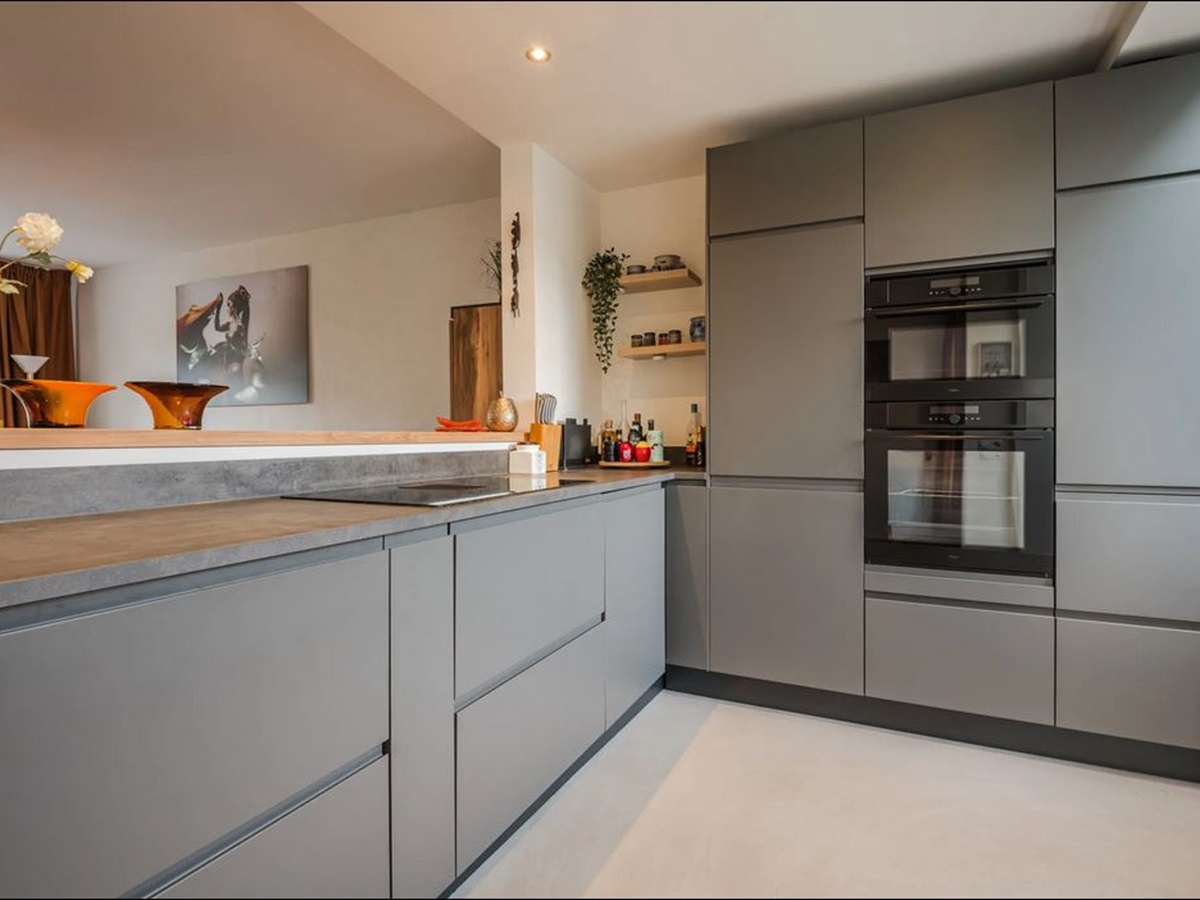<br />
Moderne keuken met grijze fronten en een naadloze betonlook gietvloer in een zachte lichte tint 