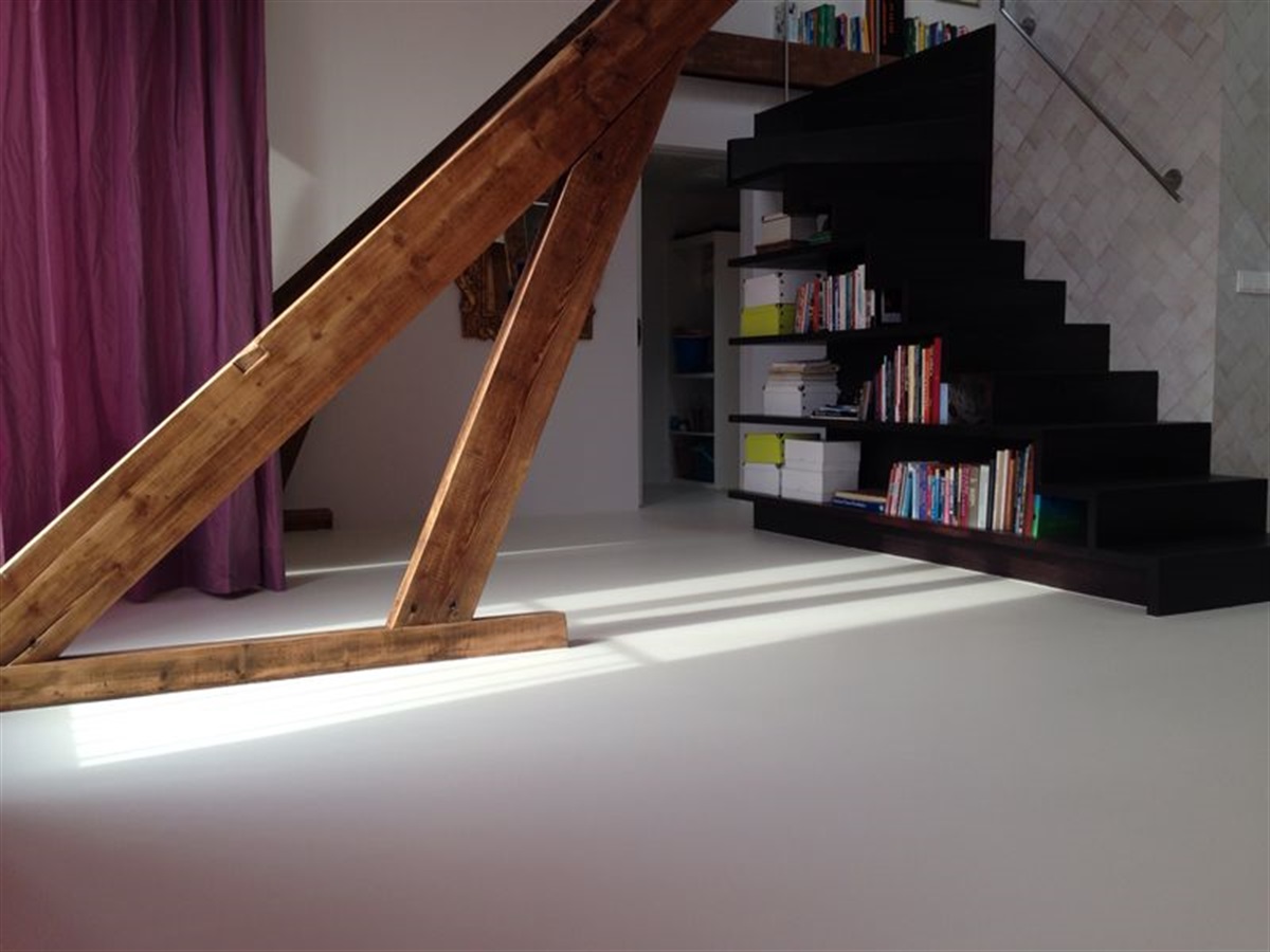 Woonkamer met houten spanten en zwarte trap op een naadloze PU gietvloer in lichtgrijs — 's-Hertogenbosch
