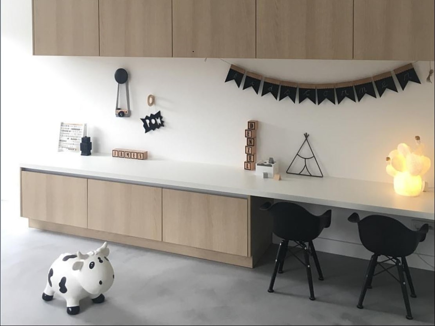 Kinderhoek met een microcement vloer in de kleur Grigio Cemento, licht houten kasten en een wit werkblad
