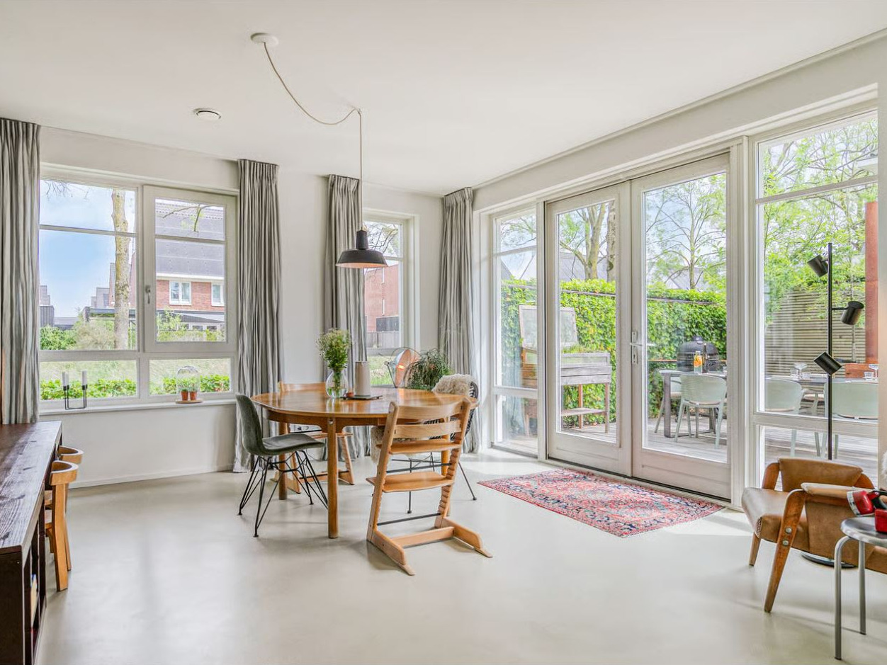 Pure Base vloer in de kleur Kiezelgrijs in een lichte eetkamer met ronde houten tafel en openslaande tuindeuren in Eindhoven
